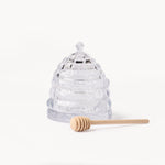 Gewurzhaus glass beehive-shaped honey jar with a matching lid and a small wooden honey dipper.