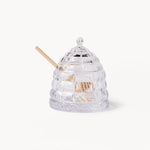 Gewurzhaus glass beehive-shaped honey jar with a matching lid and a small wooden honey dipper.
