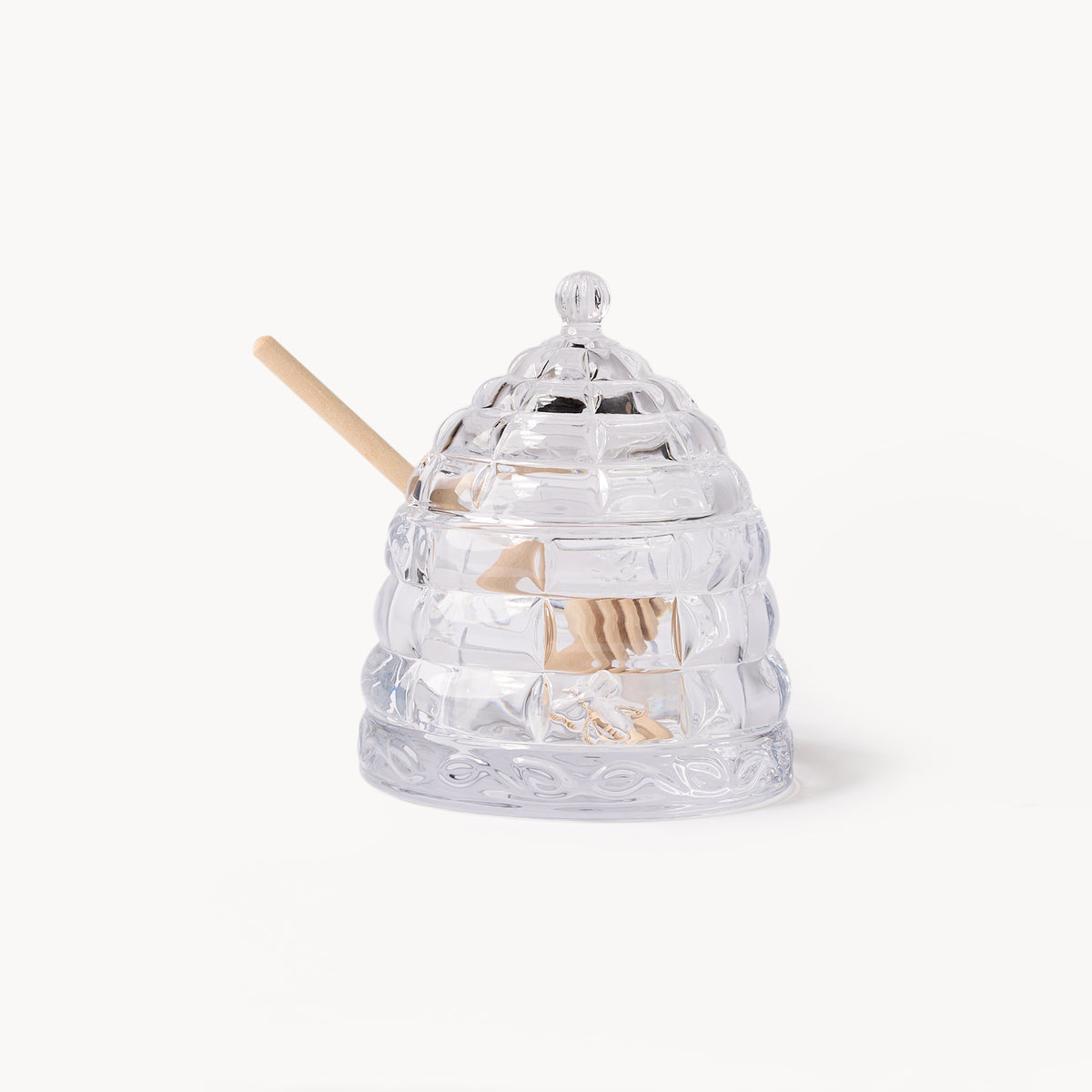 Gewurzhaus glass beehive-shaped honey jar with a matching lid and a small wooden honey dipper.