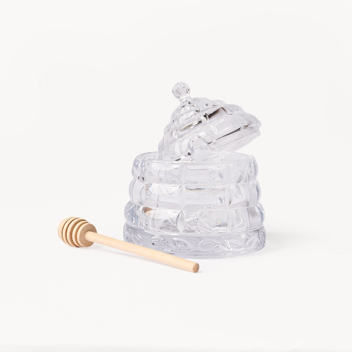 Gewurzhaus glass beehive-shaped honey jar with a matching lid and a small wooden honey dipper.