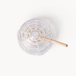 Gewurzhaus glass beehive-shaped honey jar with a matching lid and a small wooden honey dipper.