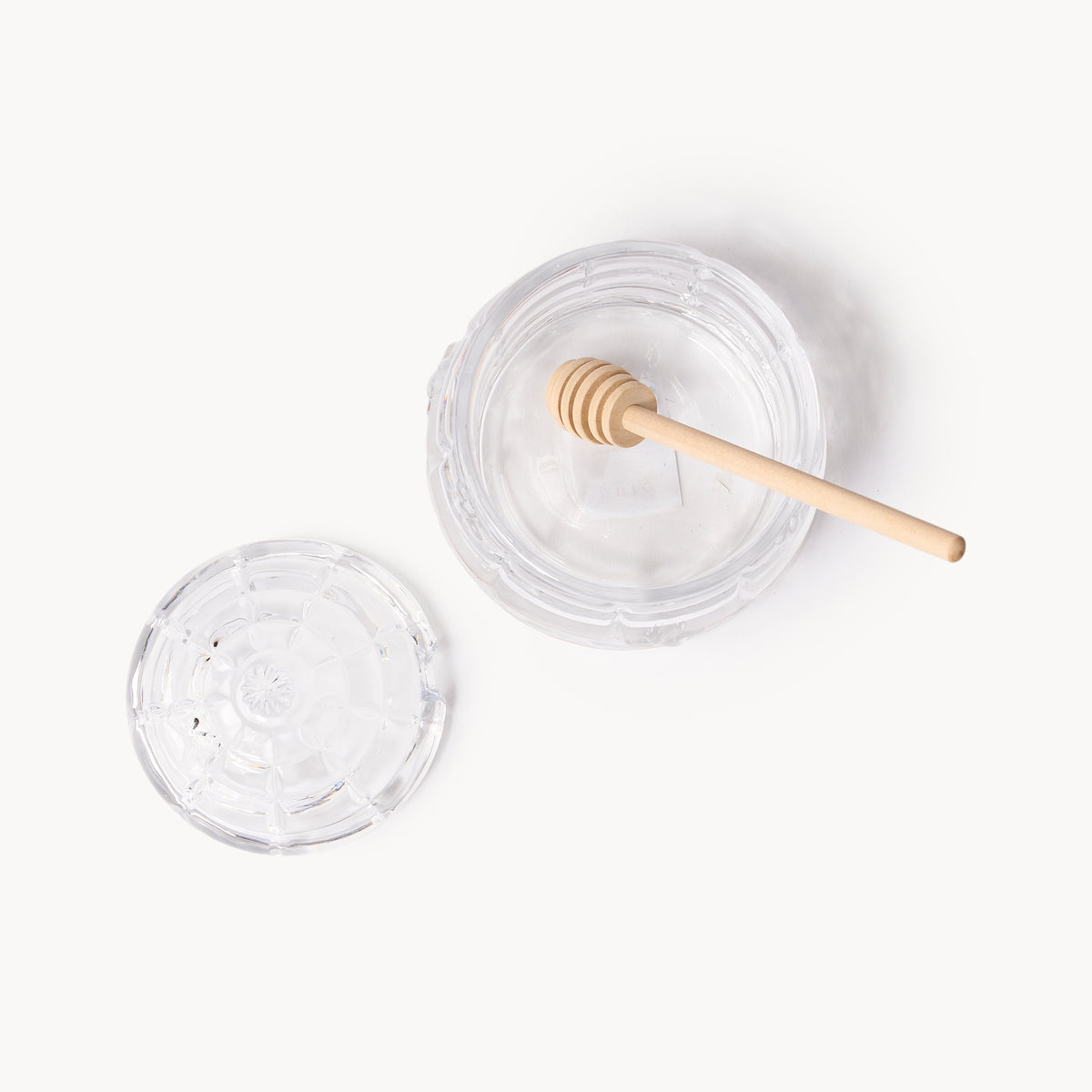 Gewurzhaus glass beehive-shaped honey jar with a matching lid and a small wooden honey dipper.