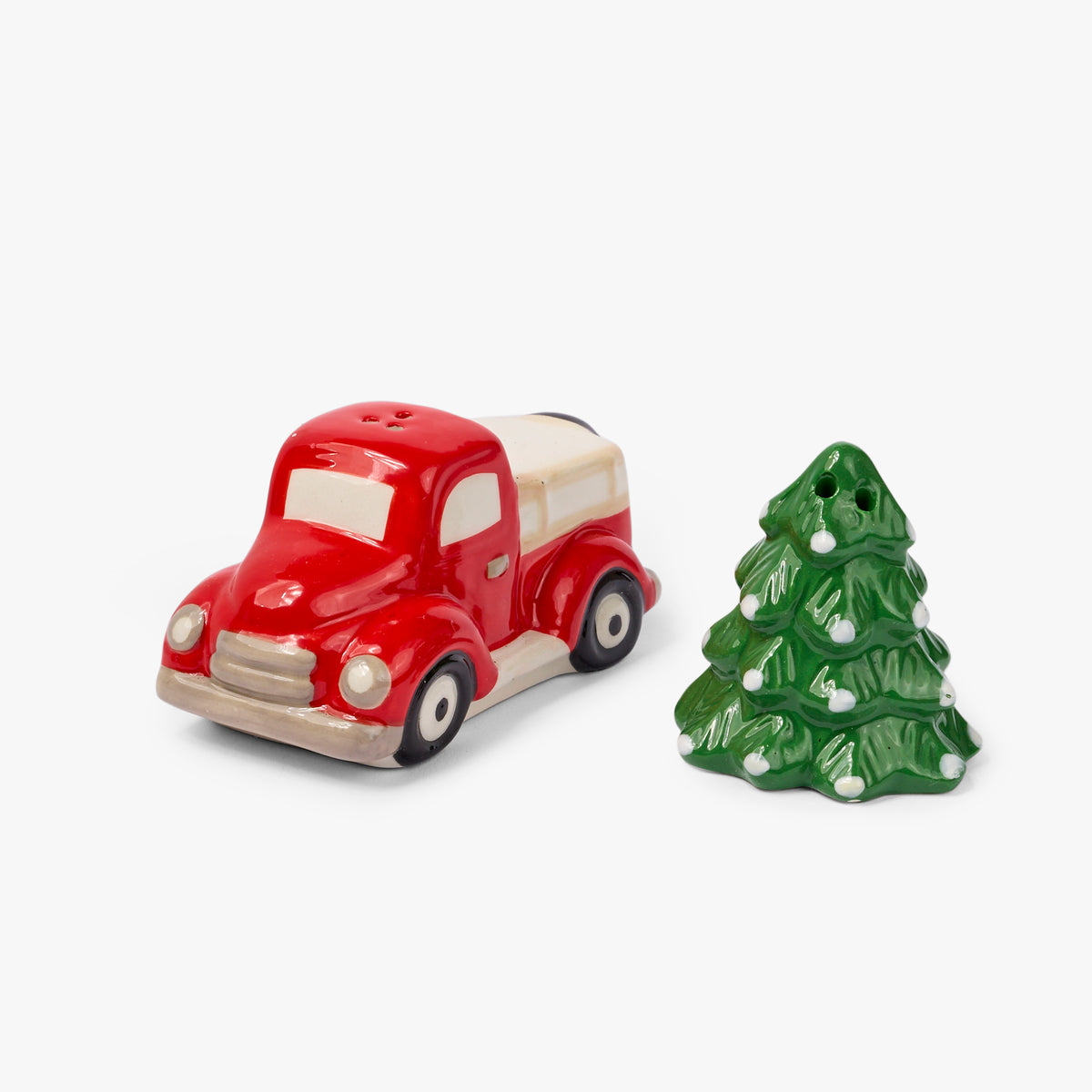 A ceramic Christmas-themed salt and pepper shaker set featuring a red vintage pickup truck and a green Christmas tree with white ornaments, set against a plain light gray background.