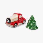 A small ceramic Christmas-themed set featuring a red vintage pickup truck with a cream-colored bed and a green pine tree with white ornaments, photographed on a clean white background.